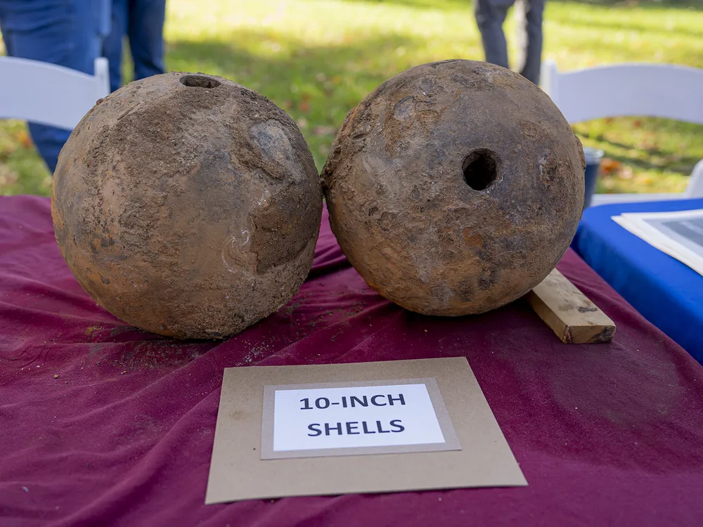 Two artillery shells sitting on a table next to a sign that reads 10-inch shells